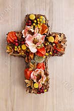 Cross made of artificial flowers and autumn plants.
