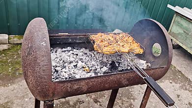 Marinated Meat Cooking in Wire Basket Over Hot Coals in Rustic Grill