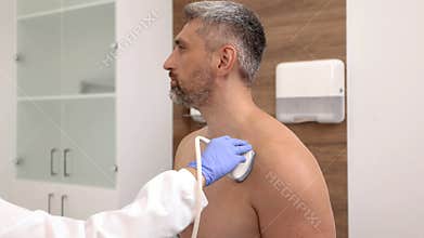 Shoulder ultrasound. Female doctor doing ultrasound scan of male patient with shoulder problem