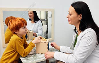 Female psychologist with boy patient in office while play therapy session. Mental health for kids