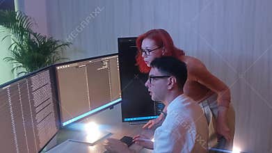 Programmers working at night analyzing code on monitors in a modern office