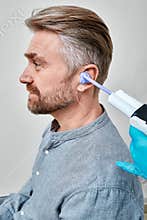 Doctor filling patient\'s ear canal with silicone material using syringe to make earmolds. Making custom in-ear
