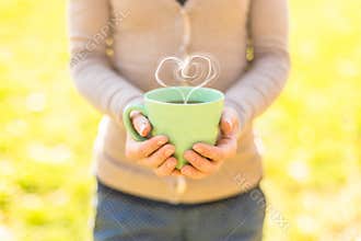 Woman holding hot tea cup with heart shape