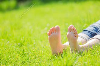 Bare feet on green grass with autumn leaves