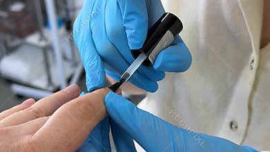 Applying clear nail polish to natural nails of an adult woman during a professional manicure treatment in a modern