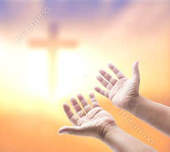 Hands Reaching Towards Blurred Christian Cross in Ethereal Golden Light and Sky Background