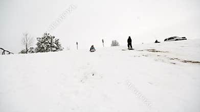 Boy and girl sledding past camera