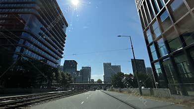Sunlit urban avenue between modern glass office towers with wide blue sky
