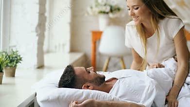 Attractive woman have fun kissing and hugging his husband in bed. Young beautiful and loving couple wake up at the
