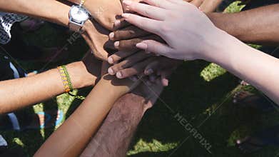 Arm of all races and colors stacked together one by one in unity and teamwork and then raised. Many multiracial hands