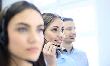 Portrait of call center worker accompanied by her team. Smiling customer support operator at work.
