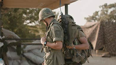 American soldier helps another to pack equipment on the military campaign