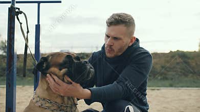 Young sporty man hug and play his bullmastiff dog outdoor at nature