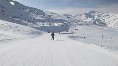 Skiers on piste going downhill