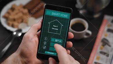 Smart home, application on the phone. A man manages various parameters of his home from a smartphone. Smart home