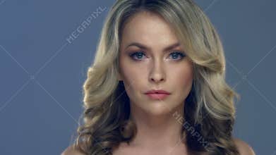 Beautiful young woman face close-up on blue background.