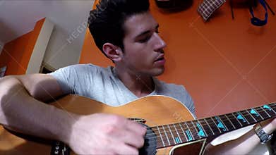 Young man on couch playing guitar at home