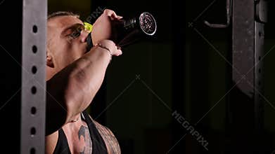 Young tired bodybuilder in a gym drinking from a shaker. 60 to 24fps 4K