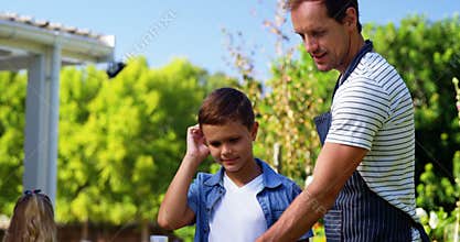 Father and son grilling sausages and corns on barbecue