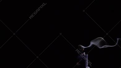 Blowing out of a black candle. Smoke on a black background slow motion