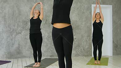 Group of young women finishing asana, practicing yoga