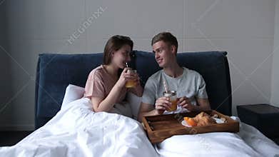 Young couple sharing breakfast in bed at home
