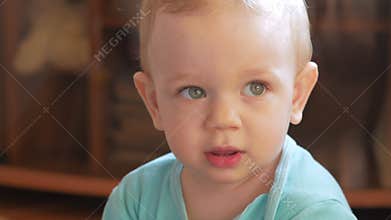 Attractive boy 2 years of playing at home with a plastic duck. The kid talks to his parents. Close-up