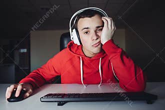 A young man in headphone use computers at night. Gamer plays games on the computer