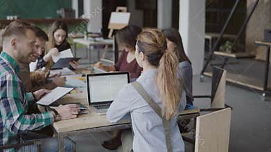 Female team leader brings documents to creative business team. Mixed race group of people meeting in modern office.