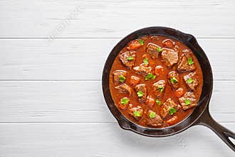 Goulash traditional homemade Hungarian beef meat stew soup food with spicy gravy in cast iron pan skillet