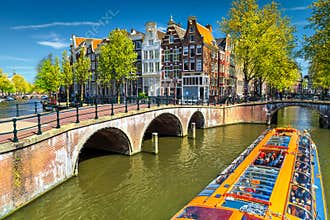 Typical Amsterdam canals with bridges and colorful boat, Netherlands, Europe