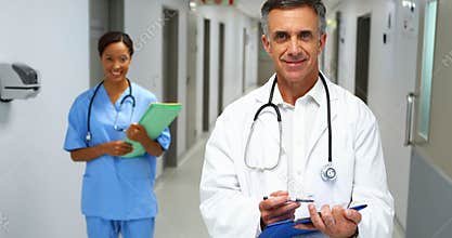 Portrait of smiling doctors with medical reports standing in corridor