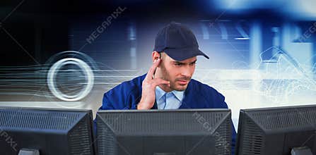 Composite image of security officer listening to earpiece while using computer at desk