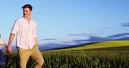 Romantic couple holding hands while walking in field
