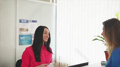 A friendly young woman administrator meets with a guest smile at a dental clinic