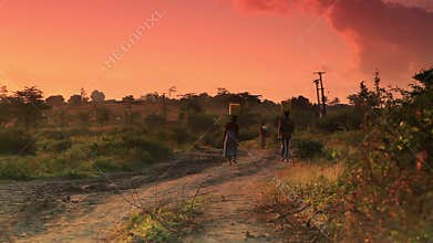 Woman carries water at dawn in kenya