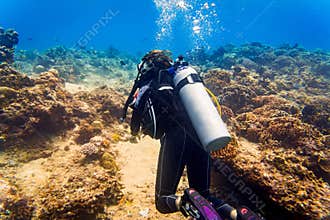 Woman diver at tropical coral reef scuba diving in tropical ocean