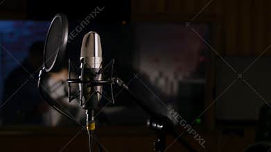 Microphone on a stand located in a music studio recording booth under low key light