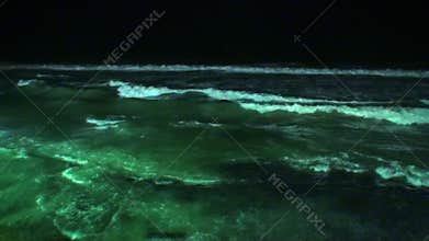 Seascape and waves glow at night in Maldives.