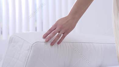 Young beautiful girl touches hand couch. A gentle touch of a hand on a white pillow in slow motion. Slow motion family