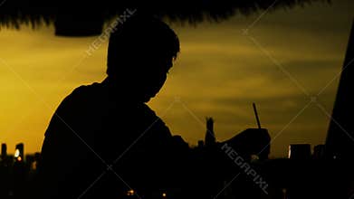 Silhouette of barman preparing cocktail at sunset outside