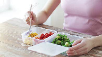 Close up of woman eating vegetables from container