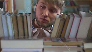 Young man browsing through the racks of books in a