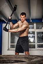Crossfit man throwing hammer on tire