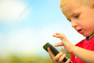 Little boy with mobile phone outdoor. Technology generation.