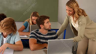 Teacher helping student with laptop