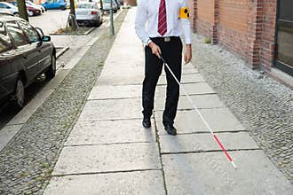 Blind man walking on sidewalk