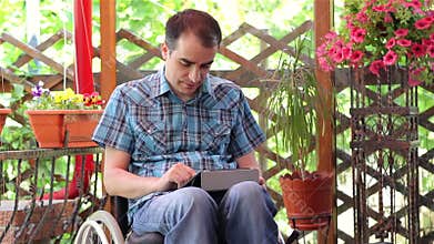 Young man on wheelchair using a tablet computer