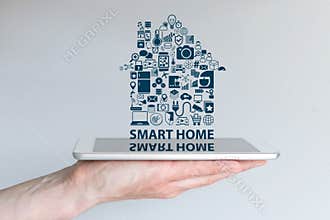 Smart home automation concept. Background with hand holding smart phone and floating text and icons.