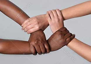White Caucasian female and black African American hands holding together against racism and xenophobia